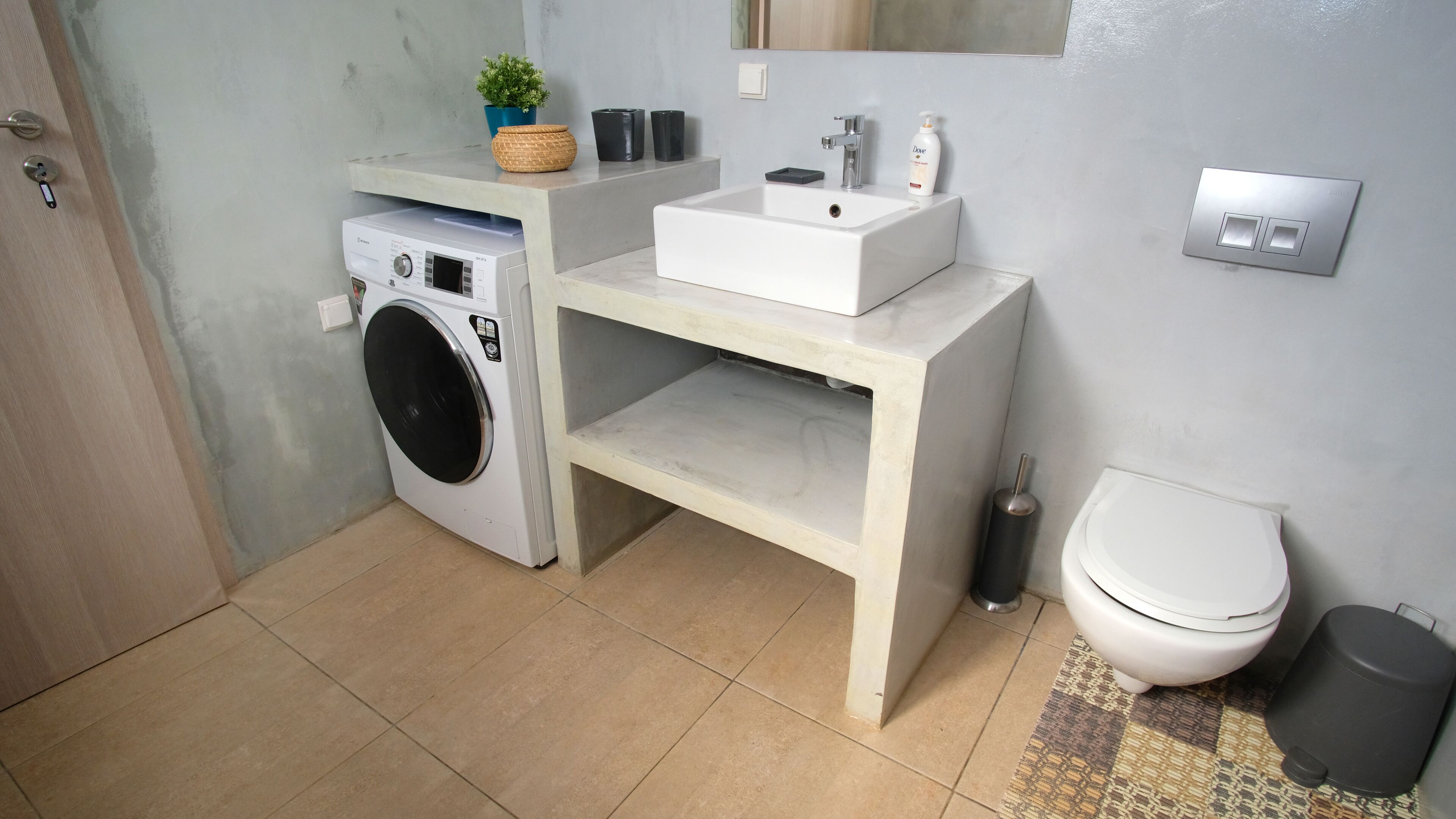 Ein kleines Badezimmer mit Waschmaschine, Waschbecken und Toilette.