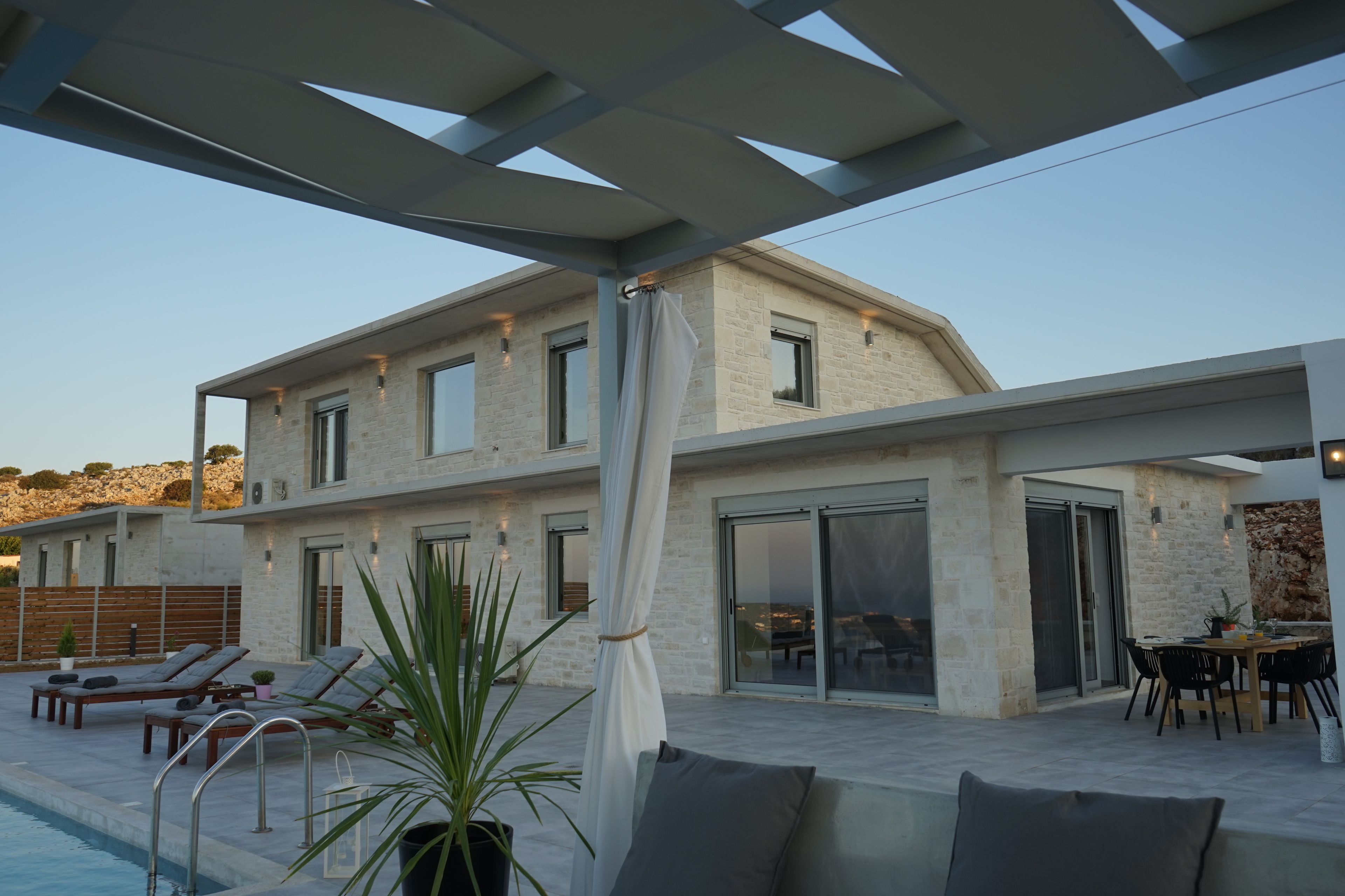 Une maison moderne dotée d’une piscine, d’un espace salon extérieur et d’un coin repas.