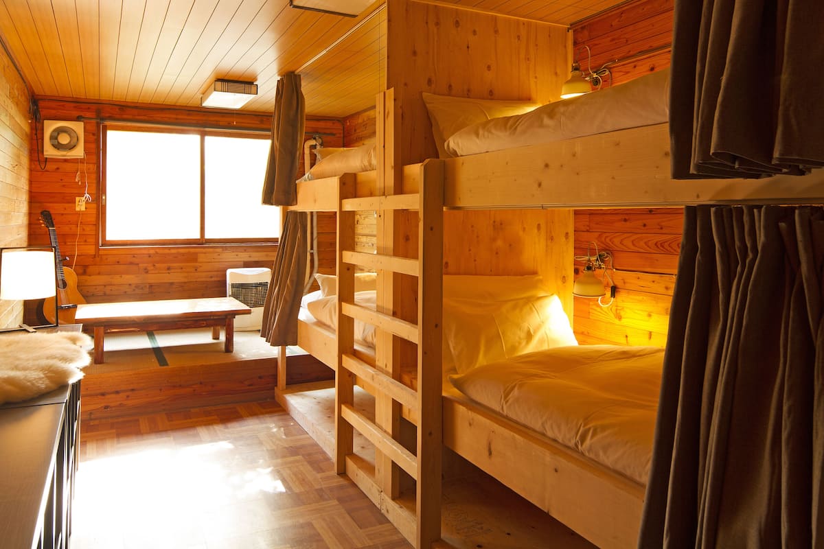 Una cabaña de madera con literas, un banco y una ventana.
