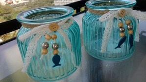 Two glass jars with decorative elements on a balcony with a view of buildings and trees.