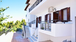 A two-story building with a staircase leading to the upper floor, outdoor furniture, and a bag on the ground.