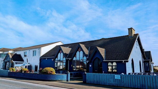 A row of houses with distinct architectural styles, including a blue building with arched windows and a white house with a sloped roof.