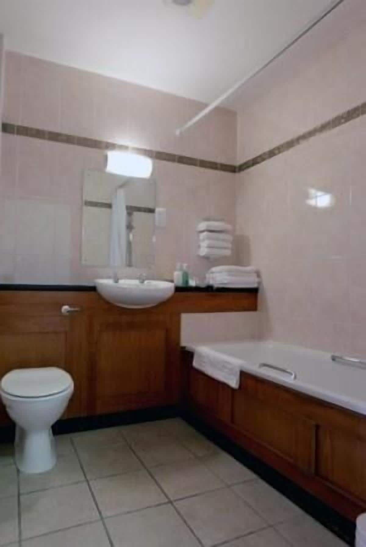 A small bathroom with a toilet, sink, and mirror.