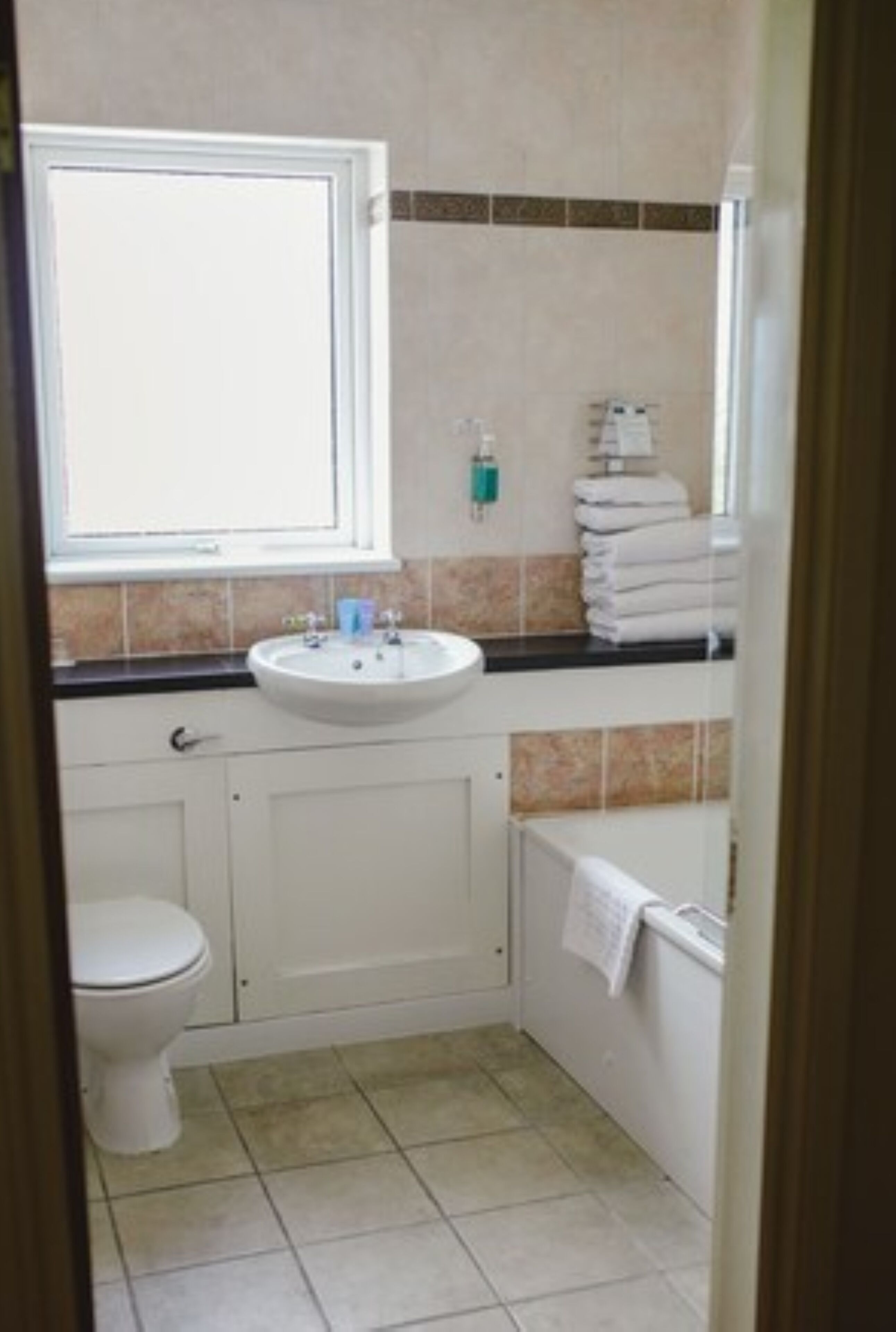Ein kleines Badezimmer mit einem weißen Waschbecken, einer Toilette und einer Badewanne.