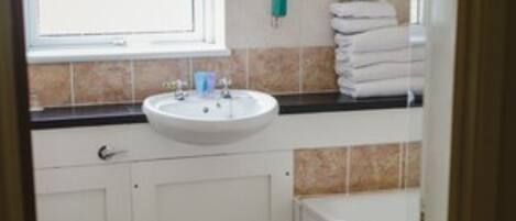 A small bathroom with a white sink, a toilet, and a bathtub.