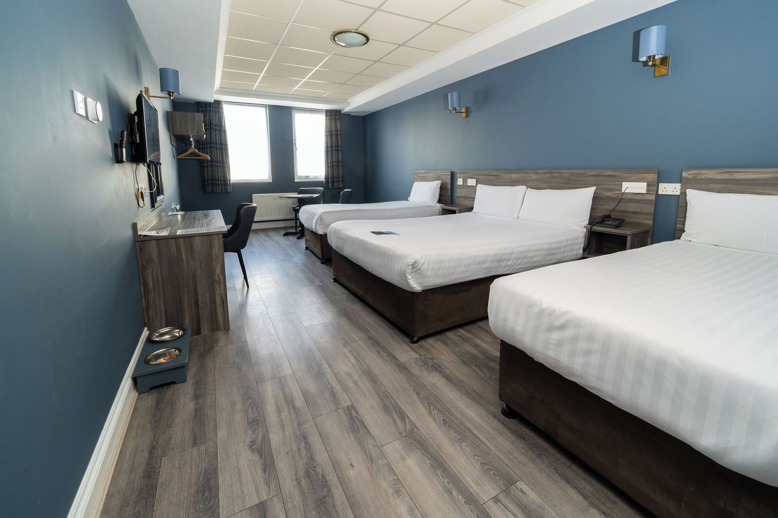 Ett hotellrum med två sängar, ett skrivbord, en stol, ett litet bord och en TV.