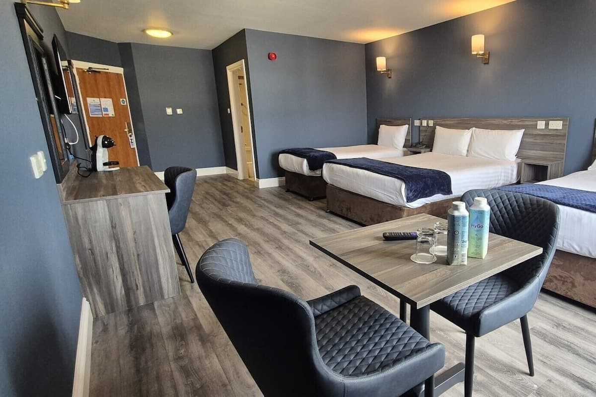 A hotel room with two beds, a wooden table, and two chairs.