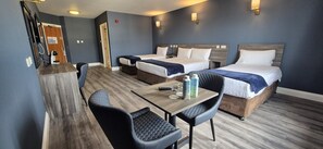 A hotel room with two beds, a wooden table, and two chairs.