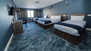 A hotel room with two beds, a desk, a chair, and a television.