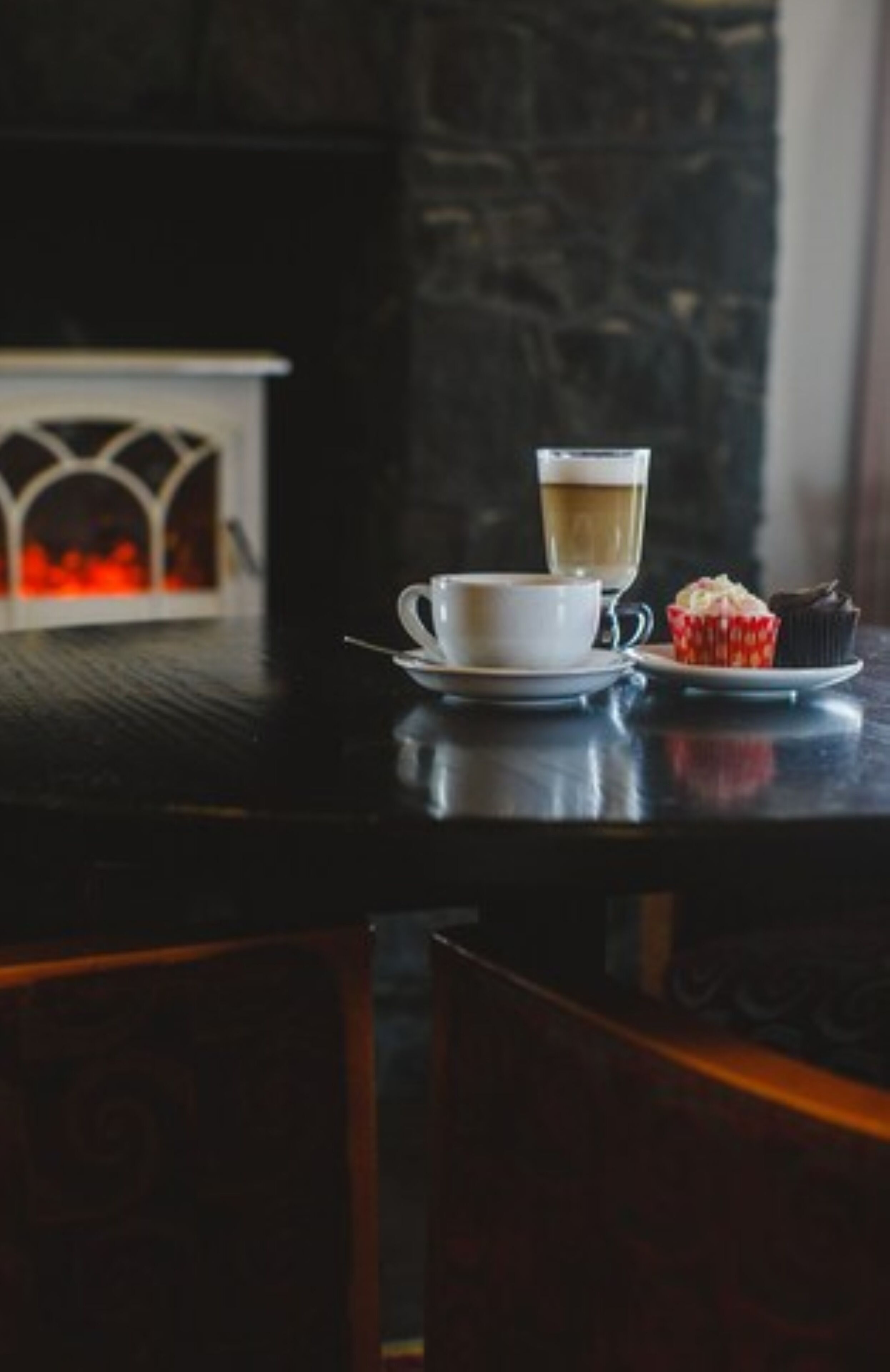 A table with a cup of coffee and a cupcake.