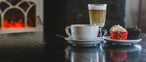 A table with a cup of coffee and a cupcake.