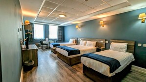 A hotel room with two beds, a desk, a chair, and a small table.