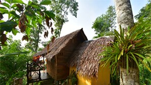 A rustic wooden structure with a thatched roof, surrounded by lush greenery and a palm tree. - Tha Khao Bay View (Ko Yao)