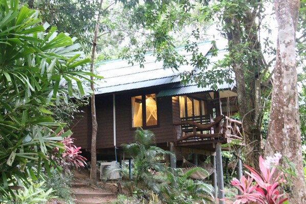 A wooden cabin with a balcony, surrounded by lush tropical vegetation. - Tha Khao Bay View (Ko Yao)
