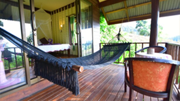 A hammock on a wooden deck, a chair, and a table with a canopy. - Tha Khao Bay View (Ko Yao)