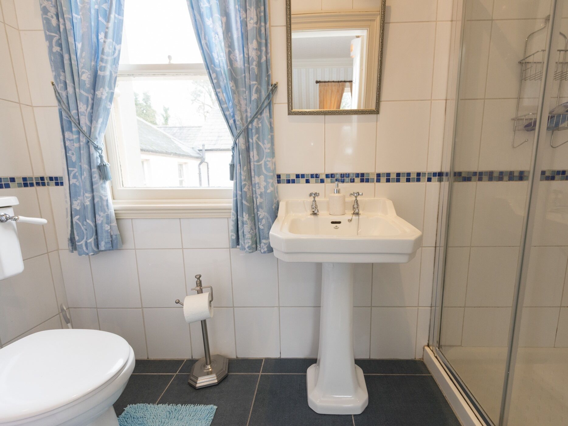 A bathroom with a toilet, sink, and shower.