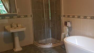 A bathroom with a glass-enclosed shower, a pedestal sink, and a freestanding bathtub.