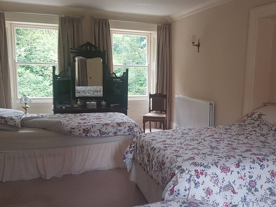 A bedroom with two beds, a dresser, a chair, and a window with curtains.