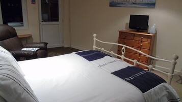 A bedroom with a bed, a dresser, a television, and a painting on the wall.