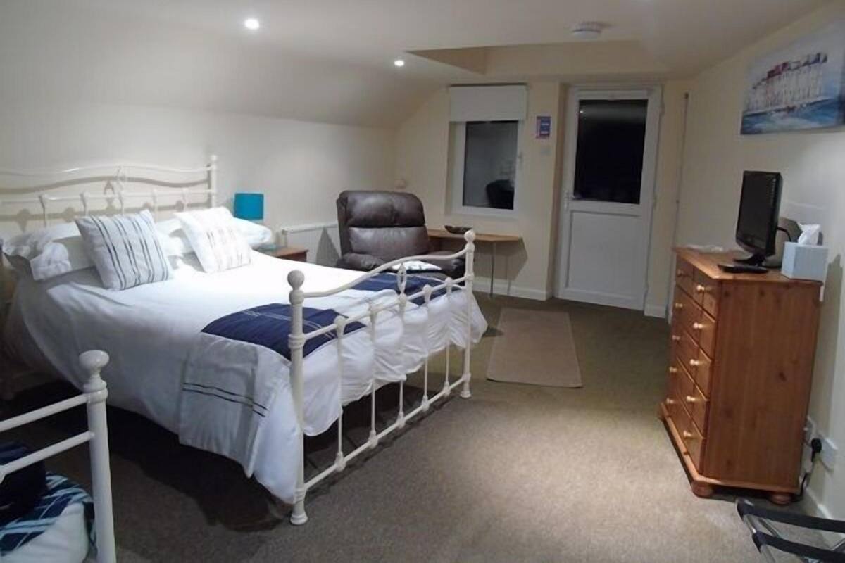 A bedroom with a bed, a desk, a chair, and a dresser.