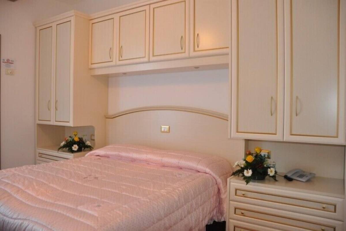 Un dormitorio con cama, mesita de noche, cómoda y armario.