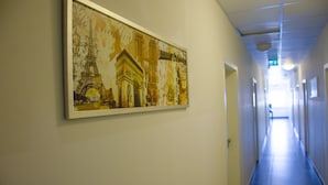 A hallway with a framed picture of the Eiffel Tower and a classical building. - Panorama Hotel (Offenbach am Main)