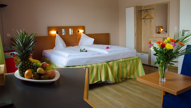 A hotel room with a bed, bedside table, and a fruit bowl. - Panorama Hotel (Offenbach am Main)