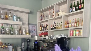 Zona de bar amb calaixos plens de garrafes de licors, una màquina de cafè i una batedora.