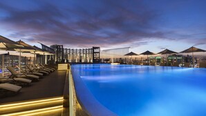 Ein Poolbereich mit Liegestühlen und Sonnenschirmen, umgeben von moderner Architektur.