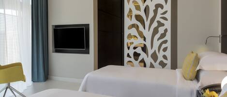 Una habitación de hotel moderna con dos camas, un televisor montado en la pared, un separador decorativo y una silla amarilla.