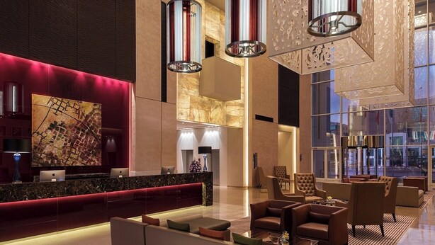 Eine moderne Lobby mit einer Rezeption, einer Sitzecke und großen Fenstern mit Blick auf die Stadt.
