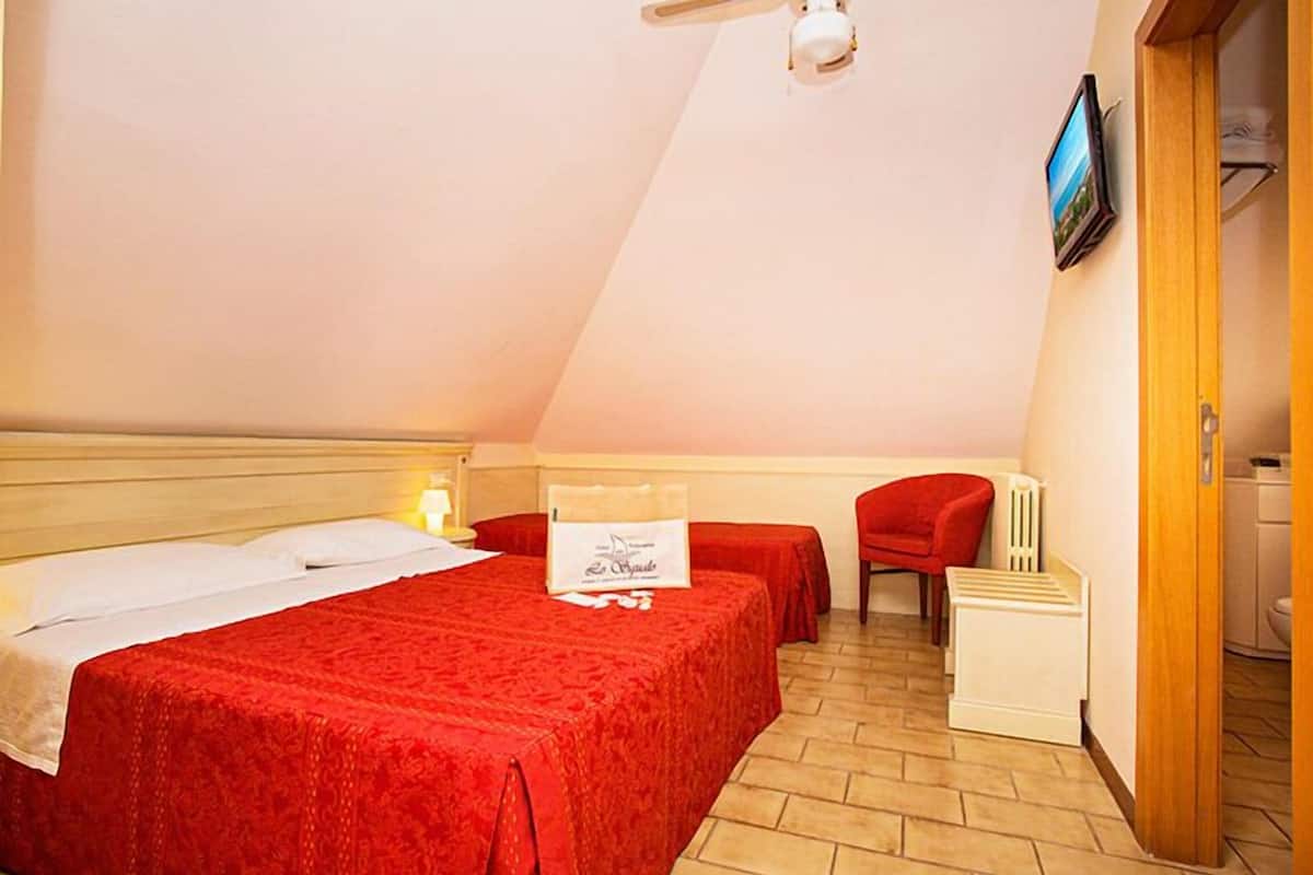 A bedroom with a bed, a chair, and a small table.