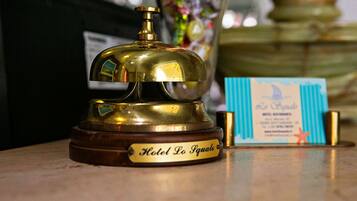 Una campana di ottone con un'etichetta che riporta “Hotel Lo Iqualo” e un cartellino con informazioni sull'hotel.