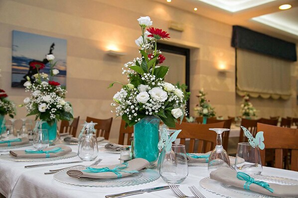 A dining table set with white tablecloths, teal napkins, and clear glassware. - Hotel Lo Squalo (Grottammare)