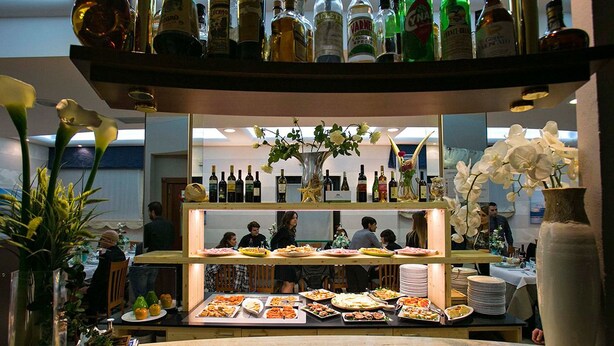 Zona de bufé con diversos alimentos y una selección de botellas de licor en estantes.