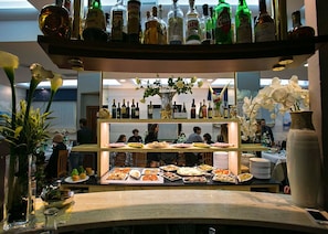 A buffet area with various food items and a selection of liquor bottles on shelves. - Hotel Lo Squalo (Grottammare)