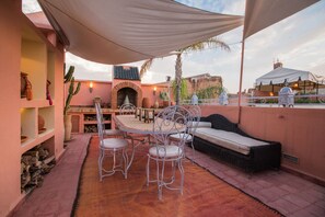 Un patio al aire libre con una mesa y sillas, un sofá y una pared decorativa.