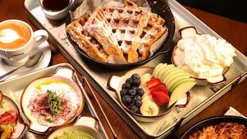 A breakfast tray with waffles, fruit, yogurt, and a skillet dish.