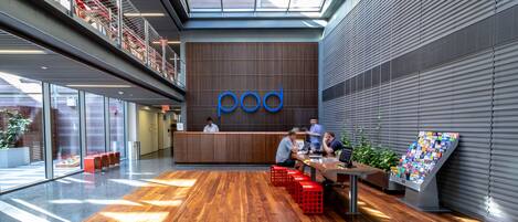 A modern interior with a reception desk, wooden flooring, and a large window allowing natural light.