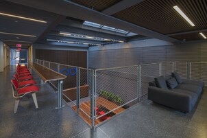 A modern indoor space with a long bench, a sofa, and a fenced area with a plant.