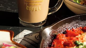 Una tazza da caffè con scritto qualcosa, un piatto di cibo e una ciotola di insalata.