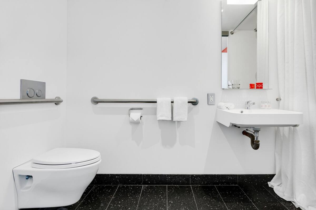 A modern bathroom with a white toilet, a sink with a mirror, and a towel rack.