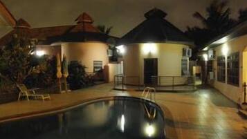 A pool area with lounge chairs and a building with a dome-shaped roof.