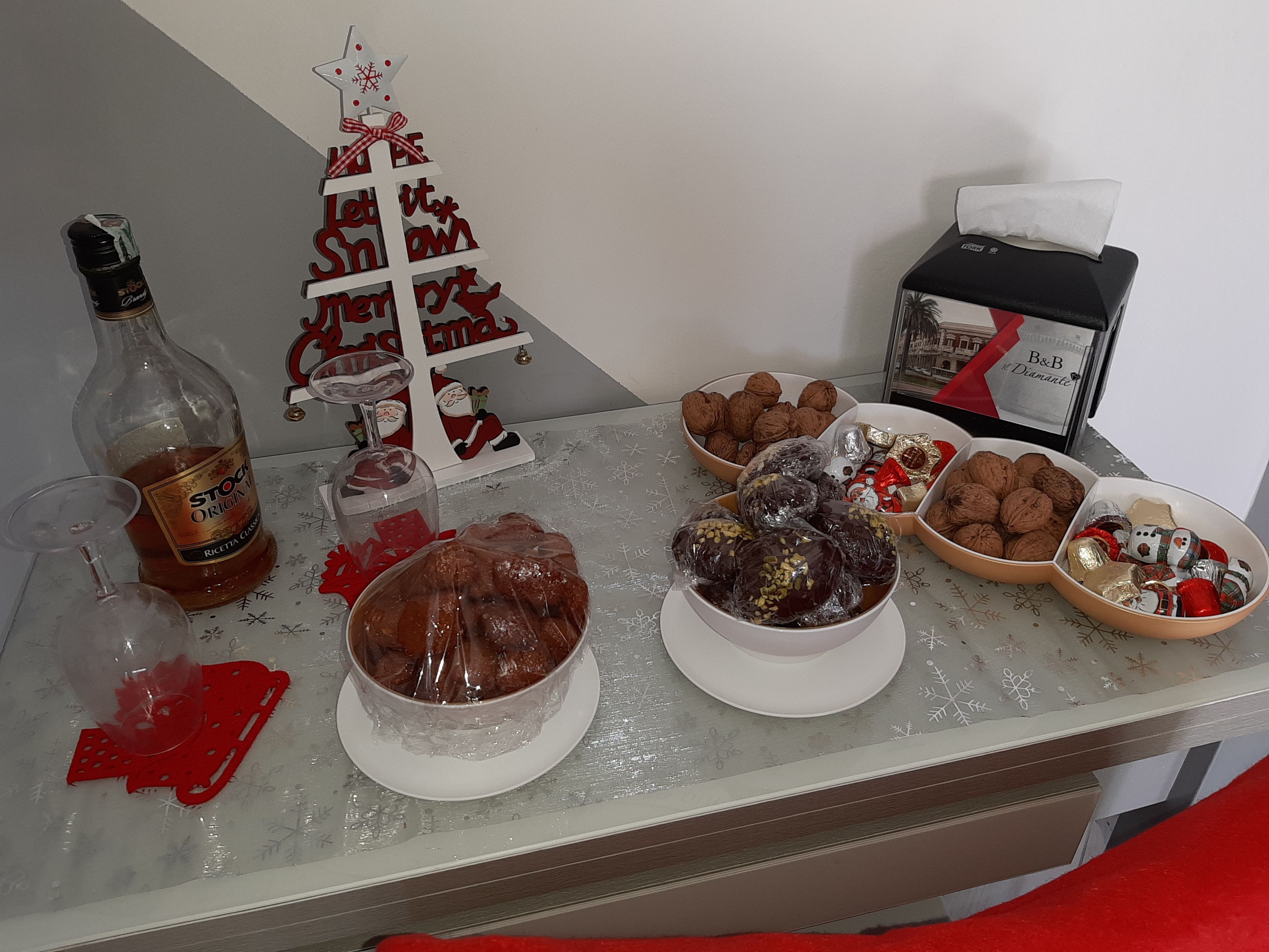 A table with various food items, a bottle of liquor, and a decorative Christmas tree.
