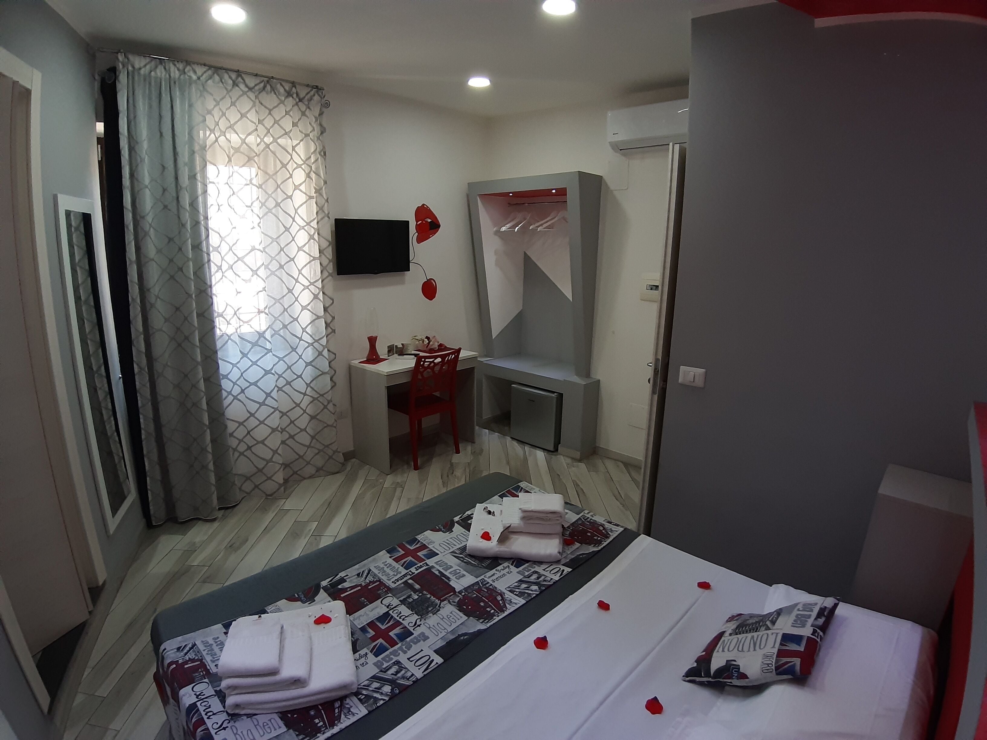 A hotel room with a bed, a desk, a chair, a wardrobe, and a television.