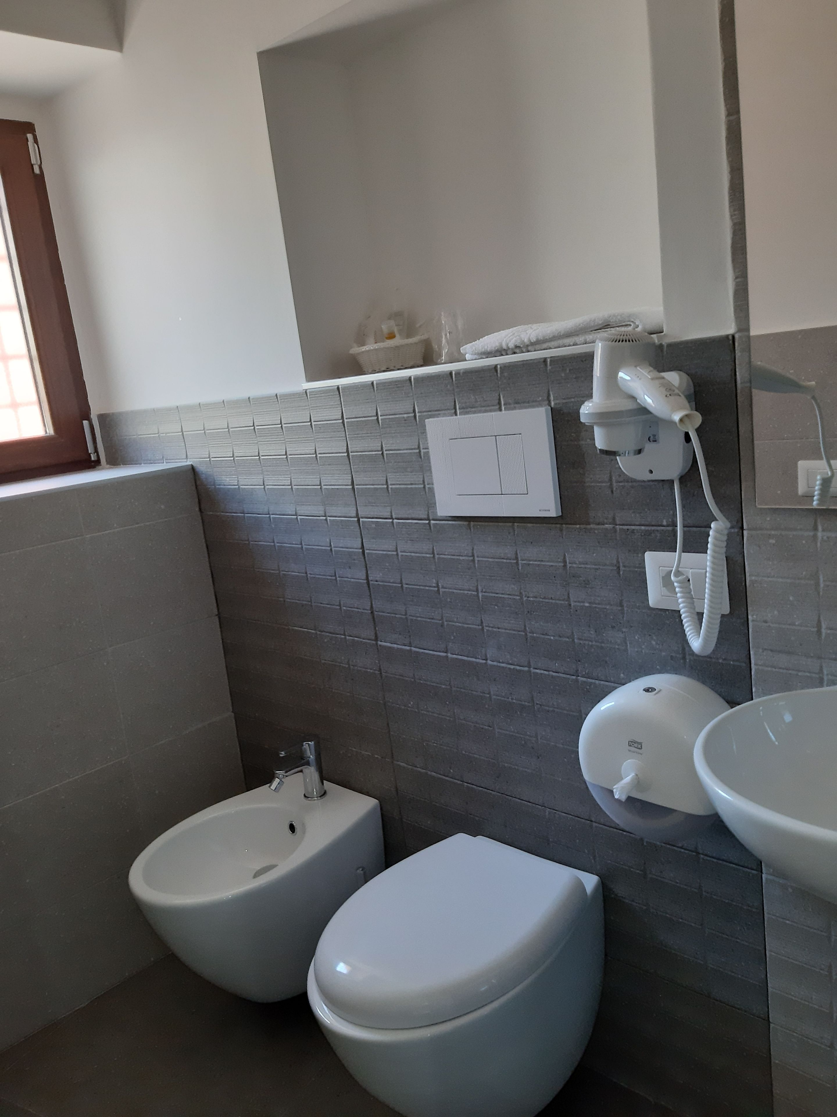 Un bagno con bidet, WC, lavandino e porta asciugamani.