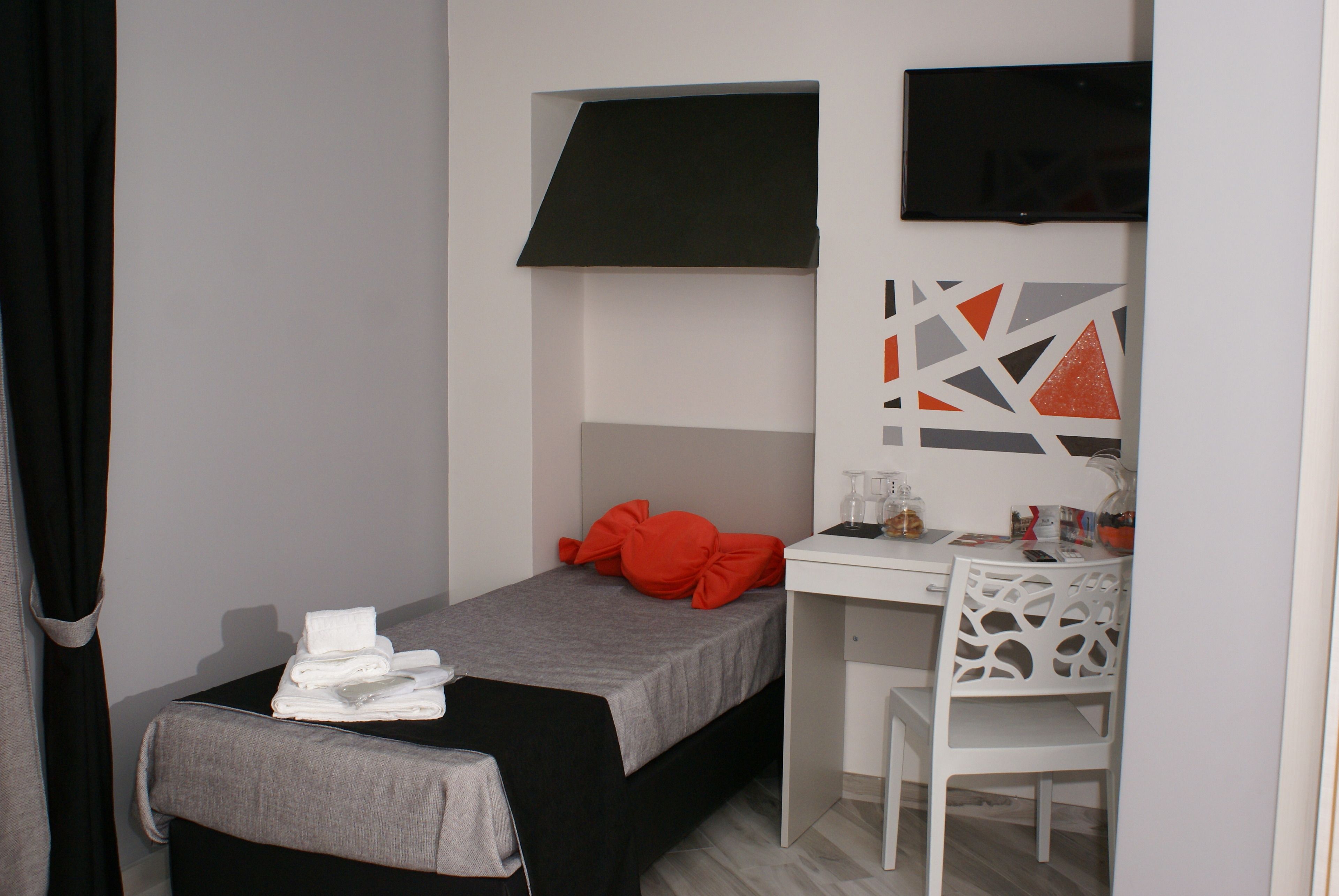 Ein kleines, modernes Zimmer mit einem Bett, einem Schreibtisch und einem Stuhl.