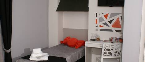 A small, modern room with a bed, a desk, and a chair.