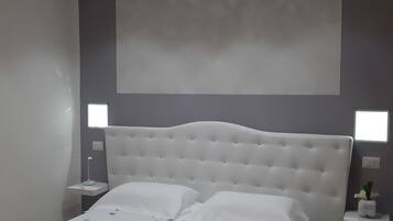 Une chambre moderne avec un grand lit, une tête de lit blanche et des tables de chevet avec des lampes.