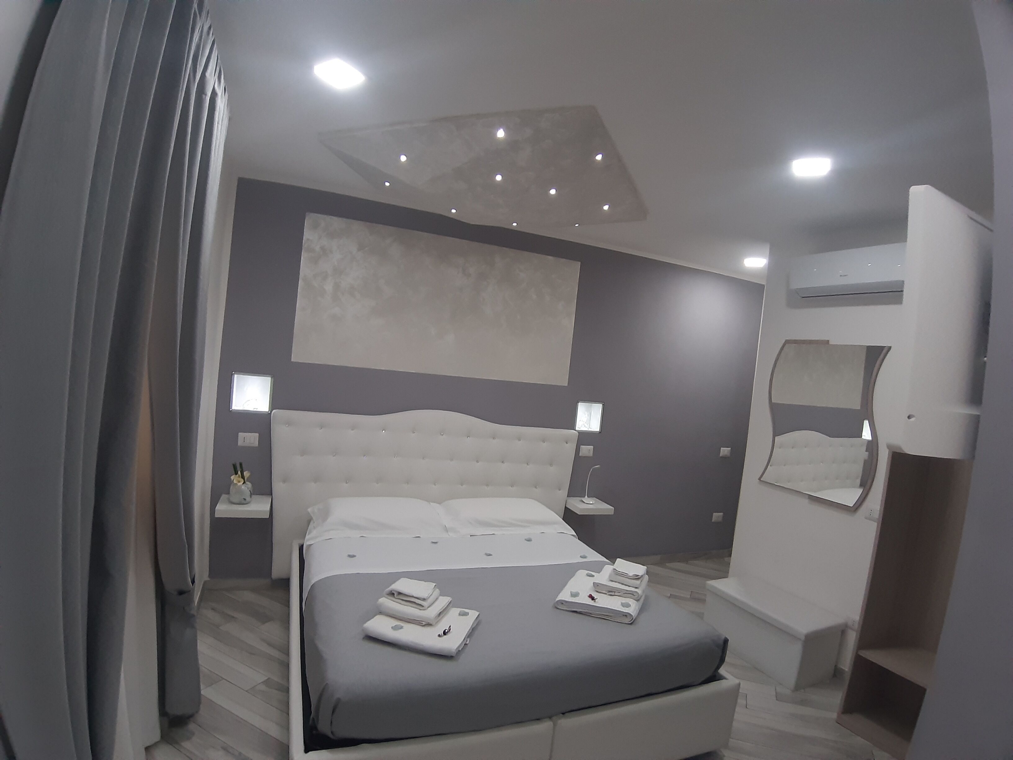Una camera da letto moderna con un letto grande, comodini, una lampada a soffitto e una panca integrata.